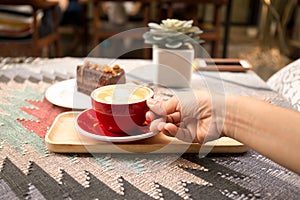 Female hand with cup of coffee and chocolate cake on the table