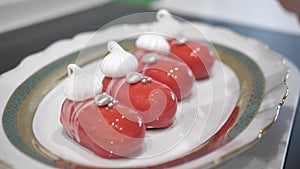 Female hand decorated red desserts with white stripes meringues, silver jewellry