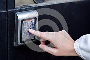 Female hand dials the access code on the electronic lock.