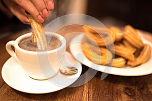 Female hand dipping churro into hot chocolate photo