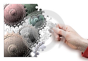 Female hand disassemble and assemble a gear - concept image in puzzle shape photo