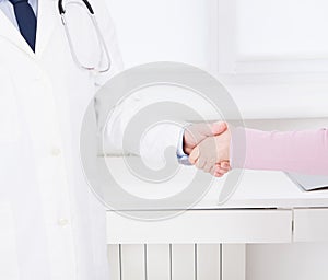 Female hand of the doctor shakes the female arm of his patient in clinic, medical office. Healthcare concept, health insurance
