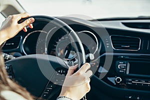 Female hand on the driving wheels. Driving a modern car steering wheel and hand close-up