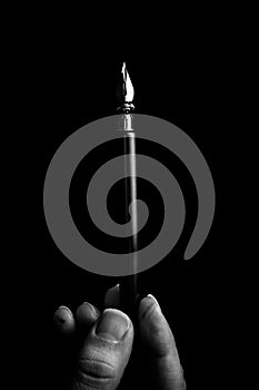 female hand elegantly holding an ink pen with a metal tip close-up on a black background. classic fountain pen isolated