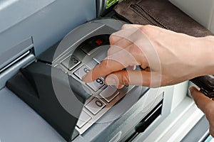 Female hand entering a secure PIN code at a cash point or ATM up close and in detail