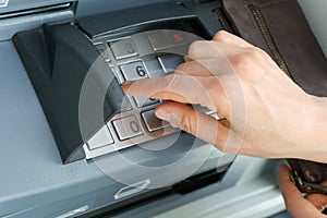 Female hand entering a secure PIN code at a cash point or ATM up close and in detail