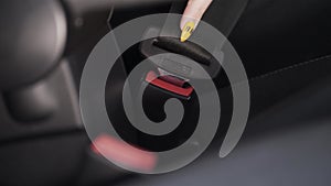 Female hand fastens a seat belt inside a car. Action. Close up of female hand with bright yellow manicure fastening seat