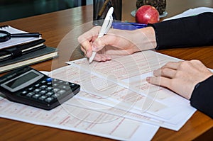 Female hand fills an Australian tax form on a table in an office.