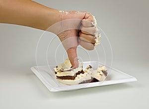 Female hand with a finger down. Thumbs down on the background of cake. Not tasty cake. Dislike cake. Concept is unlike.