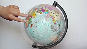 A female, hand with fingers steps on the earth globe.