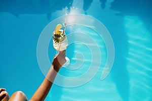 Female hand with fresh coctail, pool on background