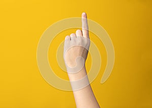 Female hand gesture shows one index finger on yellow