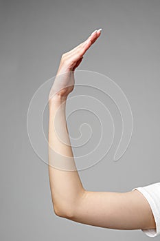 Female hand gesturing sign against gray background close up