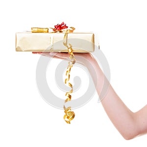 Female hand giving christmas golden gift box with ribbon. Holiday.