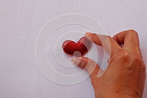 Female hand giving red mini heart on paper white pattern beautiful background