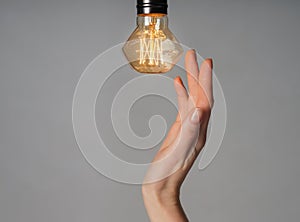 Female hand with glowing light bulb on grey background