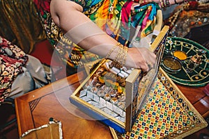 Female hand with golden bracelets open luxury box with traditional candy sweets