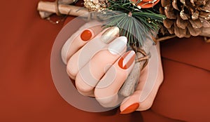 Female hand with golden Christmas nail design. Red and gold nail polish manicure. Female hand hold New Year decoration