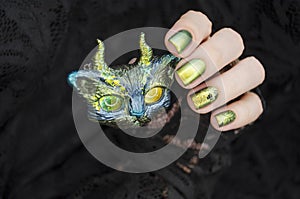 Female hand with green nail design. Multichrome shimmer Halloween nail polish manicure