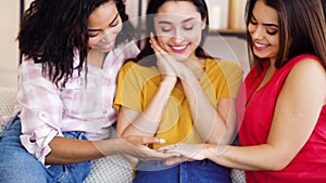 Female hand of happy bride with engagement ring showing it to friends at home