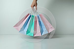 Female hand hold colorful paper bags on white background