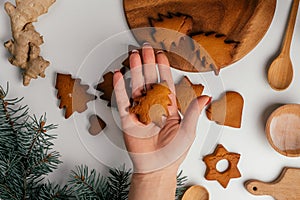 Female hand hold cookie over Christmas gingerbread cookies in form of stars and Christmas trees. Top view