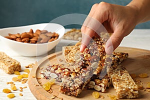 Female hand hold granola bar on wooden background with granola bars