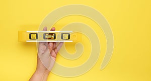 Female hand hold plastic yellow level tool with capsules on a yellow background