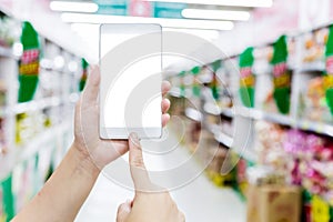 Female hand hold smartphone at supermarket and checking shopping