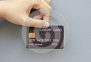 female hand holding a black credit card mockup with security chip embedded on a gray background