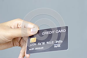 female hand holding a black credit card mockup with security chip embedded on a gray background with copy space