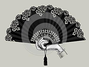 Female hand holding the black open fan with a tassel