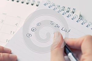 Female hand holding black pen writing To Do List prioritized by