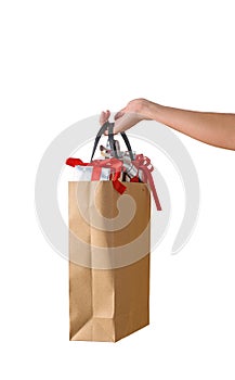 Female hand holding blank brown papaer shopping bags full of gift boxes ornamented