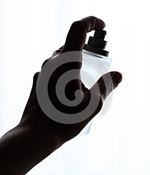 female hand holding bottle of perfume on a white backg