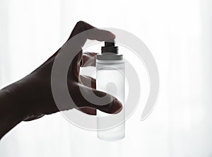 Female hand holding bottle of perfume on a white backg