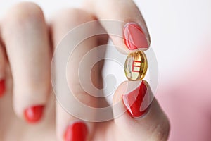 Female hand holding capsule with vitamin E.