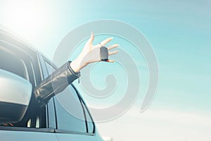 Female hand holding car key, young woman in car on blue sky background