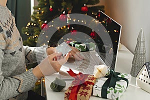 Female hand holding card and using laptop for Christmas online shopping. Holiday online shopping concept. Winter holidays sales,
