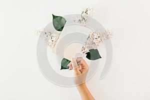 Female hand holding card white background lilac branches Flat la