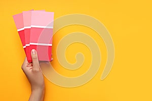 Female hand holding color palettes on yellow background