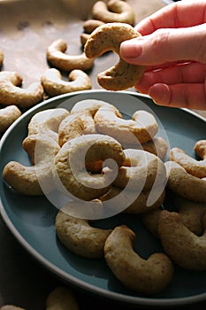 Female hand holding cookie, close up, walnut cookies on green plate