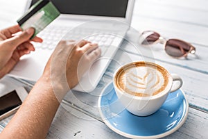 Female hand holding credit card using laptop.