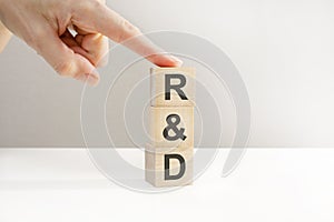 Female hand holding a cube with letter R, R and D letters on wooden cubes, research and development concept