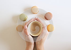 The female hand is holding a cup of coffee with macarons. White backgrounds. Flat lay, top view