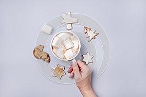 Female Hand Holding Cup of Hot Cocoa or Chocolate with Marshmallow Light Blue Background Homemade Gingerbread Cookies Top View Fla