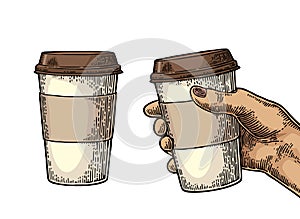 Female hand holding a disposable cup of coffee with cardboard holder and cap.