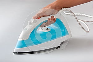 Female hand holding electric steam iron