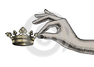 Female hand holding in fingers a gold crown