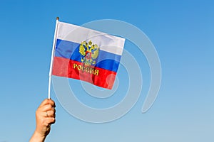 Female hand holding flag of Russia against blue sky